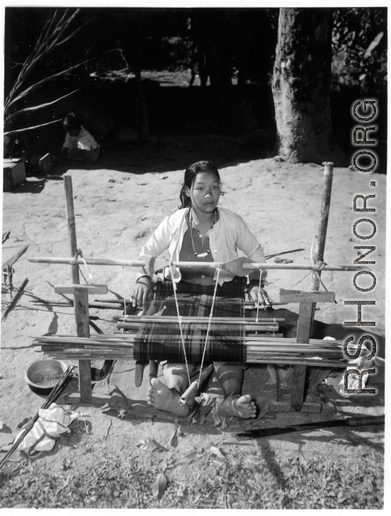 Local people in Burma near the 797th Engineer Forestry Company--A woman weaves on a loom in Burma.  During WWII.