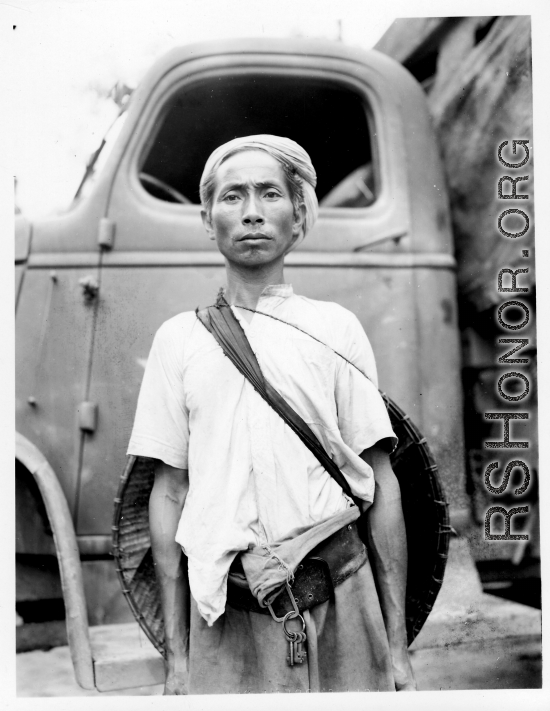 Local people in Burma near the 797th Engineer Forestry Company--A man poses in front of GI truck.  During WWII.