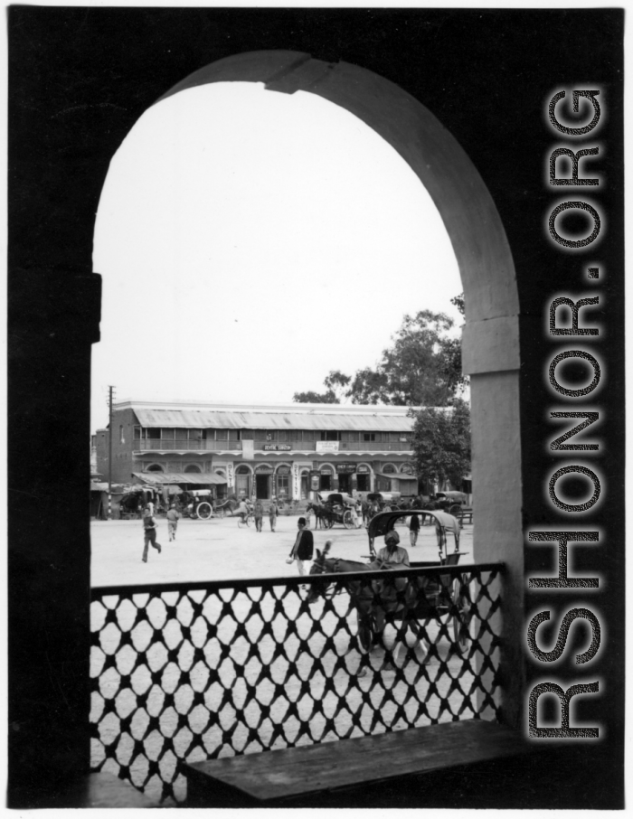 View out through archway to street and shops.  Scenes in India witnessed by American GIs during WWII. For many Americans of that era, with their limited experience traveling, the everyday sights and sounds overseas were new, intriguing, and photo worthy.