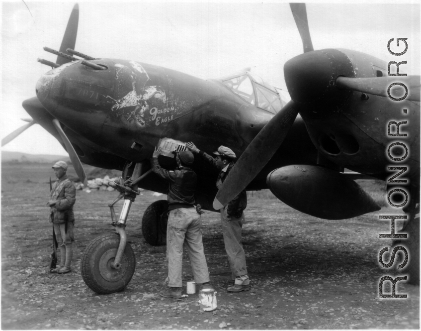 The P-38G Lightning fighter plane "Golden Eagle" (#42-13437 ) gets another bomb emblem after another mission, while Chinese guard keeps watch. #7871  Piloted by Capt Billie Beardsley.  This plane was a member of the 51st Fighter Group 449th Fighter Squadron "Twin Tailed Dragons"(thanks  jbarbaud).