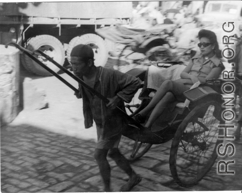 Wealthy woman rides rickshaw in China during WWII.