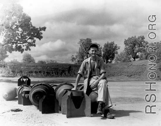 An American at a base in China sitting on bomb tail fins.  (Image from the collection of Eugene Wozniak)