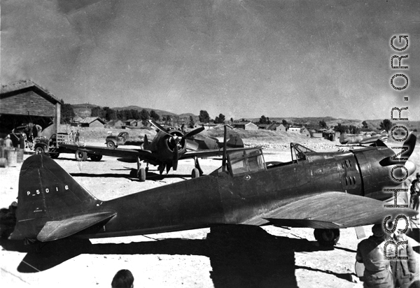 A captured Japanese A6M2 "Zeke", re-painted in Chinese Air Force (CAF) colors, with Chinese serial 'P5016'.  The aircraft directly behind the 'Zeke' is a P-43 "Lancer" flown by the CAF.  The aircraft are probably at Kunming--because of  the 23 Fighter Group P-40 in the background on the right.  (information provided by Tony Strotman)