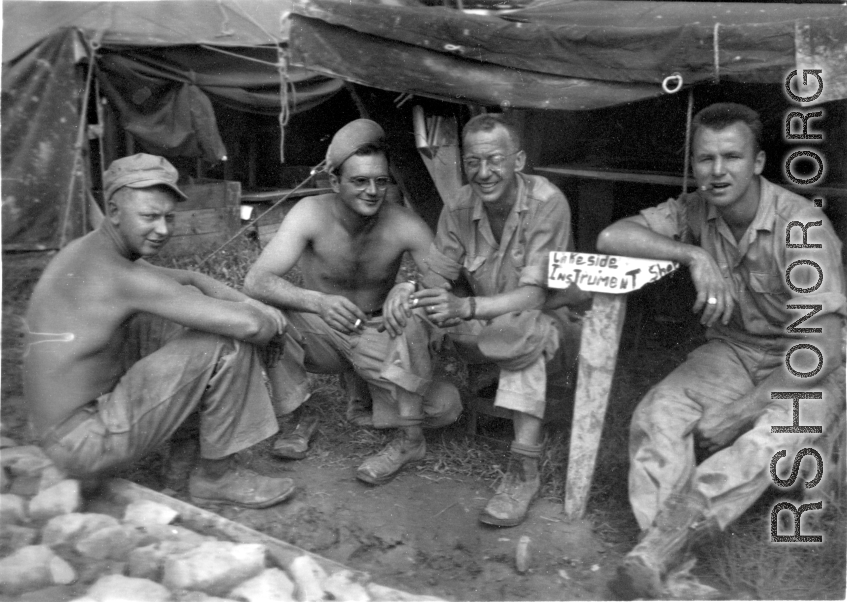 GIs in front of instrument shop tent in Liangshan, China: "This Motley Crew Is Goofing Off In Front Of Our First Class Instrument Shop In Liangshan, China. Left To Righ: Steenrod, Brantl, Wolfe, and Bukey."