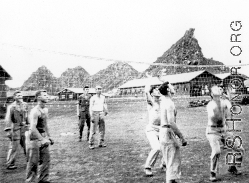 "This is some of the 396th guys playing volleyball in our hostel area at Kwelin, China. I cannot identify all of them but I do recognize "Doc" Savage...Joe Wiley...Caples, and our 1st sgt. Ed Gardner.  The unique mountain formation seen in the background of this photo was located alongside the runway at Kwelin, China and is still there to this day."