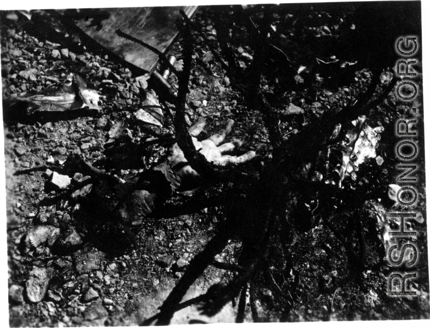 The horrors and costs of war--A severed human hand lies among the burned and melted wreckage of an airplane crash in the CBI during WWII.