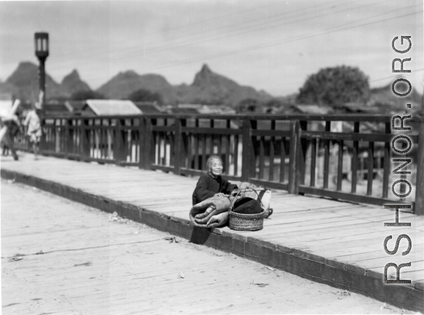 A tired elderly refugee resting on a bridge in Guilin in summer/fall 1944, in front of the Japanese advance.  From the collection of Hal Geer.