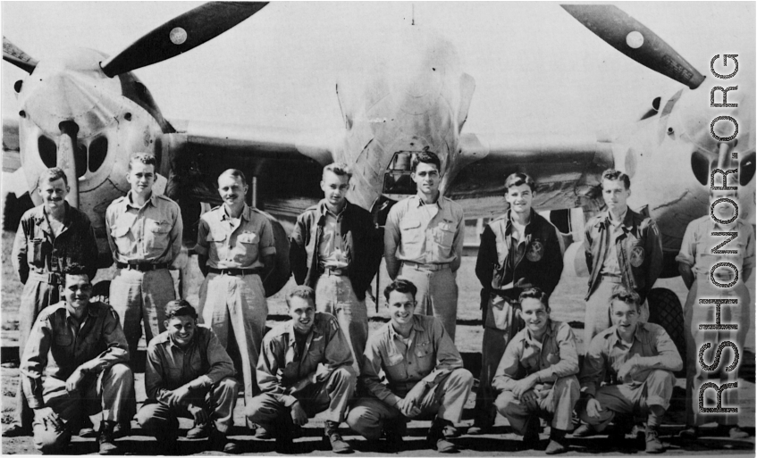 Men from the 21st Photographic Reconnaissance Squadron pose for a group shot in front of an F-5 (a variant of the P-38).