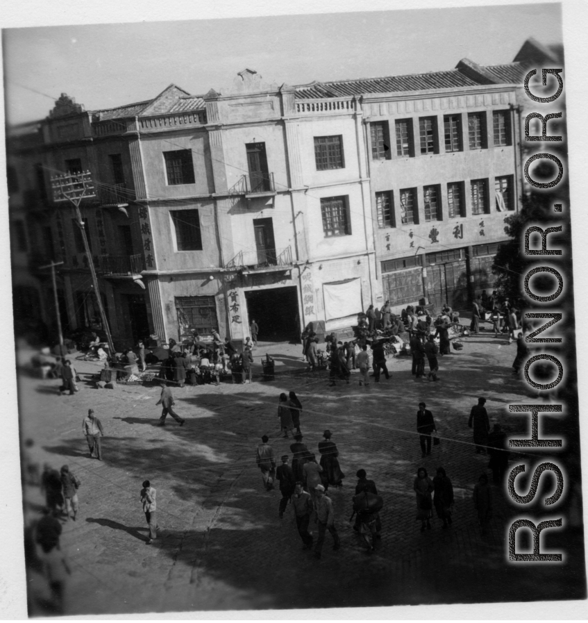 Scenes around Kunming city, Yunnan province, China, during WWII: Corner with curbside sellers and cloth market.