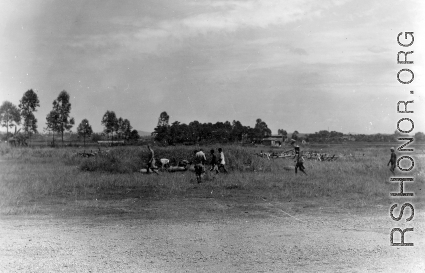 Personnel collect up some errant bombs that are strangely scattered in the grass near the base. During WWII.