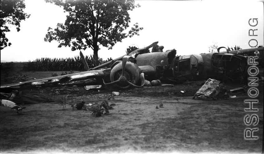 Wrecked B-25 Mitchell bomber on the ground in the CBI. The wreck was apparently at an air base, and probably on take-off, as the craft is sprayed with fire-retardant foam, and bombs are scattered about the wreck site. During WWII.