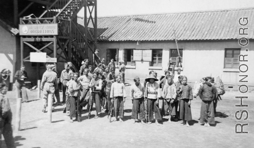 A Chinese and American search party being organized to find an American pilot whose plane had gone down in a location pinpointed by the 23rd Fighter Control Squadron, which was one of its duties.  The sign on the stairway in the background reads "Air Transport Command Operations."  From the collection of David Axelrod.