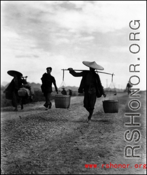 People carrying shoulder poles in China during WWII.