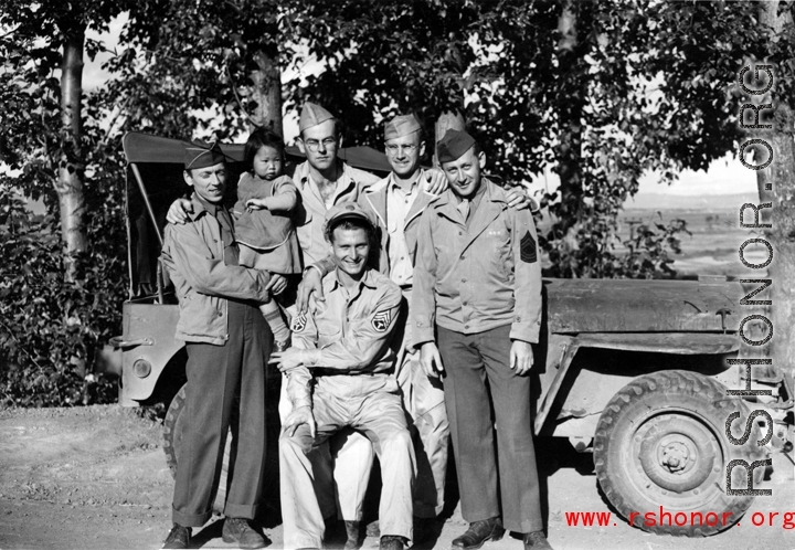 Smiling GIs pose with small child from well-to-do family in China, during WWII.