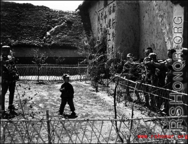 American and Chinese servicemen exchanging a "Ding Hao" thumbs up with a young Chinese boy the CBI.