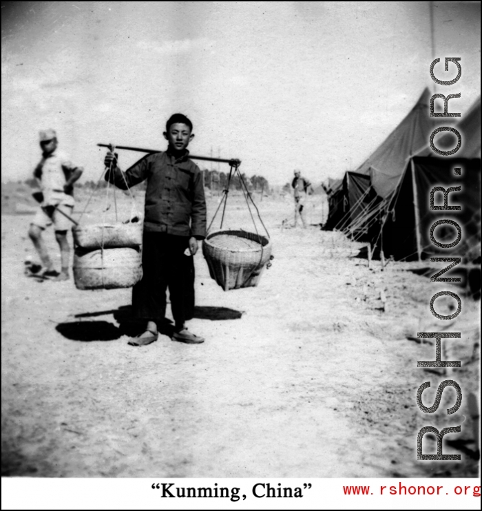 Scenes around Kunming city, Yunnan province, China, during WWII: Worker shoulders pole at GI tent camp.