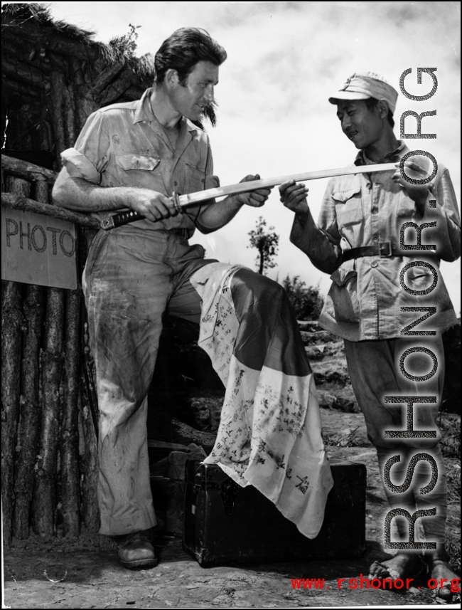 An American GI and and Chinese soldier examine Japanese flag and sword. During WWII in the CBI.