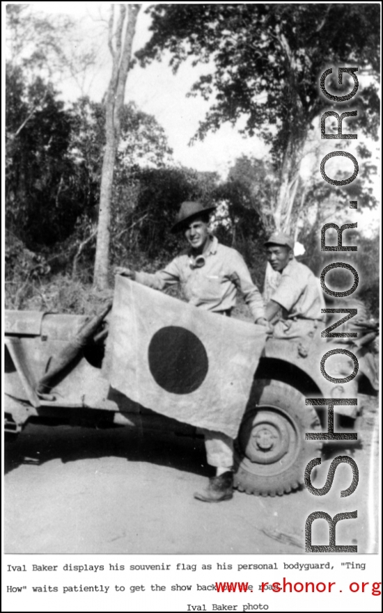 Ival Baker shows souvenir captured Japanese flag, while his bodyguard watches on. During WWII, in China.  Photo from Ival Baker.