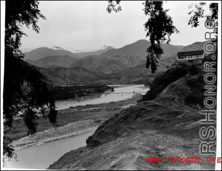 A river valley in SW China, either Yunnan or Sichuan, during WWII, with a pedestrian rope bridge across the river.  Photo from Dorothy Yuen Leuba.