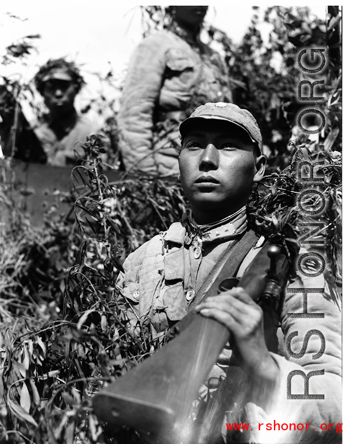Chinese soldiers with equipment ready and covered in camouflage during exercises in southern China, in Yunnan province, including this Nationalist soldier with rifle over shoulder.