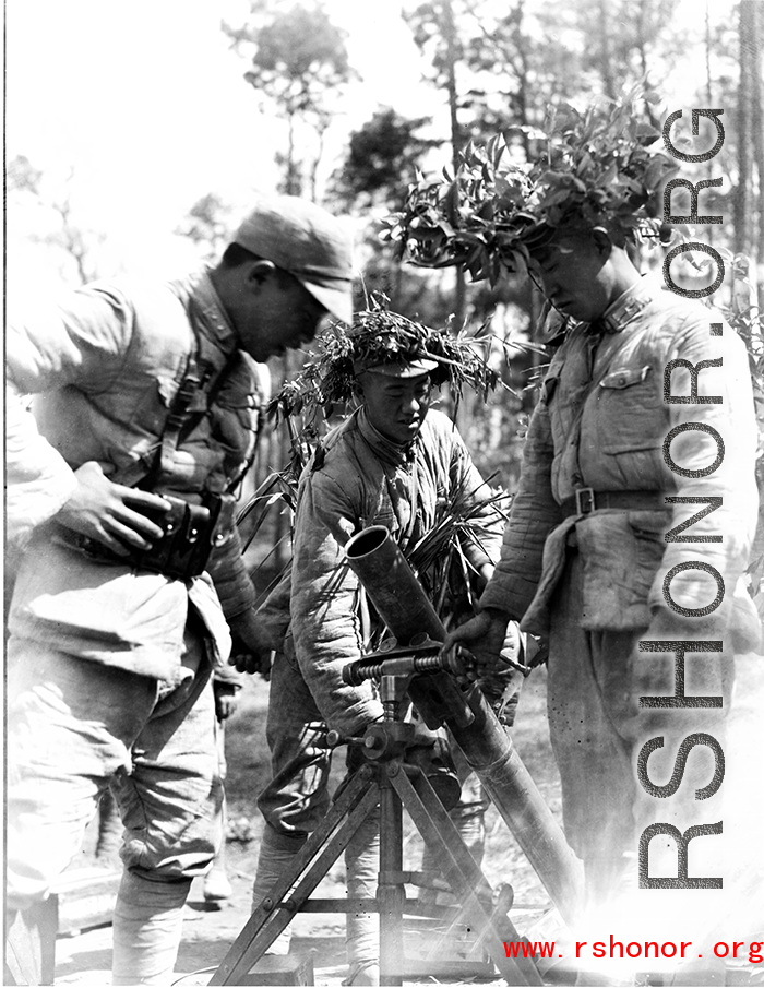 Chinese soldiers with mortar ready, and covered in camouflage during exercises in southern China, in Yunnan province. Despite the appearance of being on their way to battle, these men are more likely in fact prepared for a demonstration or honor parade.