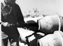 An African-American serviceman inserts the M-5 igniter into the burster well of the a M-76 500-pound incendiary bomb, making certain that the pipe lugs of the igniter are to the rear. China.