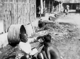 A little roadside barbering in the CBI, either Burma or India.