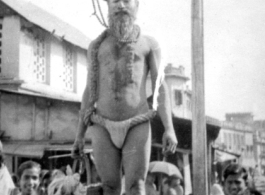 An Indian fakir and interested crowd look at cameraman during WWII.