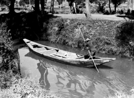 A man poles a small boat on a canal in Kunming, Yunnan province.  From the collection of Eugene T. Wozniak.