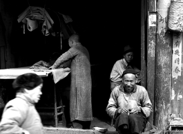 A small shop with local people and  in China, including a cobbler and tailor.  From the collection of Eugene T. Wozniak.