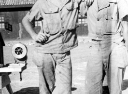 "Elmer Bukey and Bob Houser in our hostel area at Kwelin (Guilin), China standing by the air raid siren. I guarantee you that siren had a lot of use because the Japanese paid us a lot of nighttime visits. We spent a lot of nights in the caves around our hostel area."