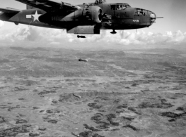 A B-25 Mitchell bomber, #448, in flight and dropping bombs in the CBI, in the area of southern China, Indochina, or Burma.