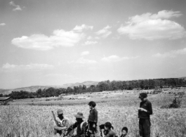 Local people in Yunnan province, China: An American GI chats with a farmer and kids at harvest time, with the grain fields ripe and ready, during WWII.