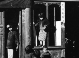 A kid in Guilin, China, climbs through shop window. During WWII.