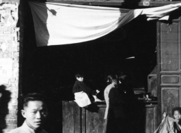 People at the door of a small retail shop in China during WWII.