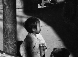 A child holds a bamboo water pipe in China during WWII.