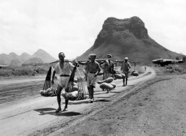 Men carrying gourds in Guilin, near the American air base, with karst mountains and B-25 bombers in the background. During WWII.  From the collection of Hal Geer.