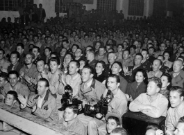 An eager audience of Chinese and American military personnel, along with Chinese civilians, view a performance in China during WWII. 