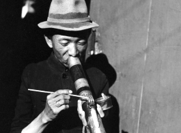 A Chinese man smokes from an elaborate decorated pipe in China during WWII.