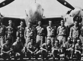 Men from the 21st Photographic Reconnaissance Squadron pose for a group shot in front of an F-5 (a variant of the P-38).