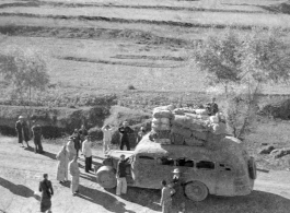 Long-haul bus in northern China during WWII, piled high with cargo. Note the wooden tires on the front, a consequence of war-time limits on rubber use.