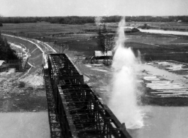 An aerial photograph of a railway bridge being bombed--a near miss--by the 491st Bomb Squadron in Yunnan or Indochina, during WWII.