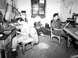 American photographers at work in the workshop in China during WWII. On the left Eugene T. Wozniak repairs a piece of photographic equipment.