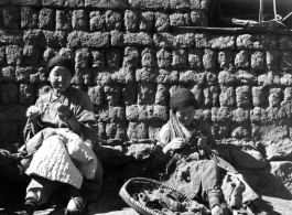 Women in a village in Yunnan mending a cotton blanket and clothing that is little more than rags. During WWII.