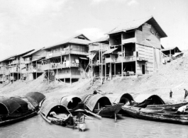 Waterside houses in China, with boats floating in the foreground, during WWII.