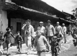 People walk on road at Yangkai village, including  a GI carrying a camera. During WWII.