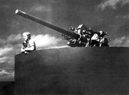 Man with microphone in gun emplacement on transport ship home from CBI to US after WWII.