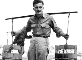 GI poses with buckets on a shoulder pole in China, during WWII.