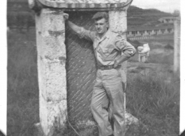 Charles Klaes leans against back of tombstone at base at Yunnan, China. During WWII.