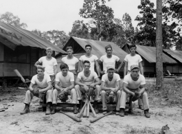 Engineers of the 797th Engineer Forestry Company pose outside tents with baseball gear in Burma.  During WWII.